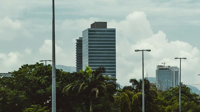 A modern high-rise office tower in Abuja against a bright, cloudy sky.